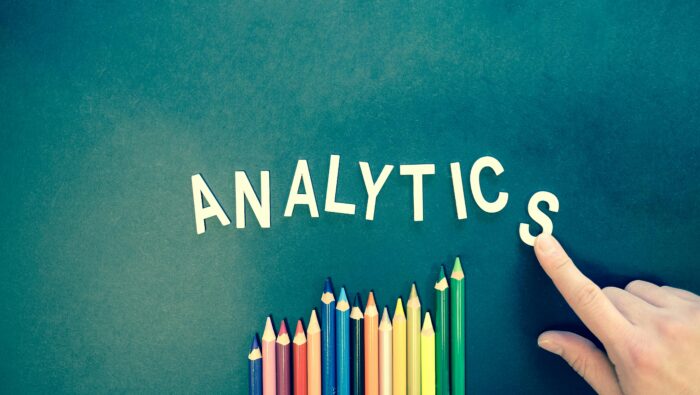 a hand pointing to the word analytics and colored pencils